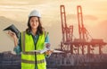 Female engineer with computer is standing in front sea port cargo crane harbor terminal Royalty Free Stock Photo