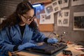 Female engineer fixing broken computer motherboard in workshop. Laptop disassembling with screwdriver at old repair shop Royalty Free Stock Photo