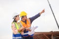 Female engineer and foreman worker checking project at building site, Engineer and builders in hardhats discussing on construction