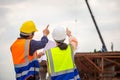 Female engineer and foreman worker checking project at building site, Engineer and builders in hardhats discussing on construction Royalty Free Stock Photo