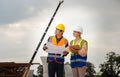 Female engineer and foreman worker checking project at building site, Engineer and builders in hardhats discussing on construction Royalty Free Stock Photo