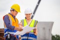 Female engineer and foreman worker checking project at building site, Engineer and builders in hardhats discussing on construction Royalty Free Stock Photo