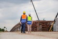 Female engineer and foreman worker checking project at building site, Engineer and builders in hardhats discussing on construction Royalty Free Stock Photo