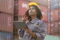 Female engineer in the hard hat uses digital tablet inspecting container box, Foreman dock worker working at shipping yard Royalty Free Stock Photo
