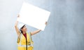 A female engineer holding a paper placard with empty space with a concrete background Royalty Free Stock Photo