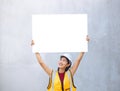 A female engineer holding a paper placard with empty space with a concrete background Royalty Free Stock Photo