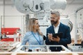 Female engineer and male production manager standing in modern industrial factory, talking about production