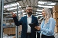 Female engineer and male production manager standing in modern industrial factory, talking about production