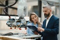 Female engineer and male production manager standing in modern industrial factory, talking about production