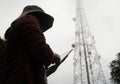 Female engineer using tablet computer checking the frequency with telecommunication towers with TV antennas and satellite dish In