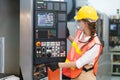 Female Engineer wear face mask with safety vest and yellow helmet operating control CNC Machinery at factory