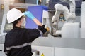 Female engineer wearing protective mask and glove to protect against Covid-19 and looking at robot CNC machine in smart factor