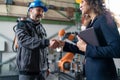 Female engineering manager and mechanic worker fist bumping in industrial factory