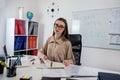 female English teacher sitting near whiteboard with rules and explains a new lesson topic Royalty Free Stock Photo