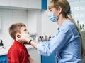 Female ENT doctor taking off or putting on a protective face mask from a boy patent before medical examination Royalty Free Stock Photo