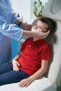 Female ENT doctor taking off or putting on a protective face mask from a boy patent before medical examination Royalty Free Stock Photo