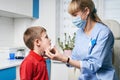 Female ENT doctor taking off or putting on a protective face mask from a boy patent before medical examination Royalty Free Stock Photo