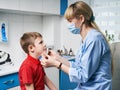 Female ENT doctor taking off or putting on a protective face mask from a boy patent before medical examination Royalty Free Stock Photo