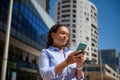 Female entrepreneur holding her modern smartphone, checking new mobile app, booking, ordering, scrolling newsfeed