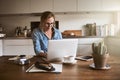 Female entrepreneur sitting in her kitchen working on a laptop