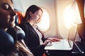 Female entrepreneur working on laptop sitting near window in an airplane