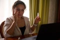 Female entrepreneur works on laptop, holding medicinal eye drops to relief digital eye strain and dryness. Ophthalmology