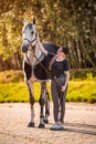 Female equestrian horse rider patting her gray horse