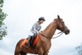 Female equestrian smiling while riding horse and holding reins