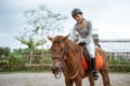Female equestrian smiling while riding horse and holding reins