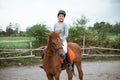 Female equestrian smiling while riding horse and holding reins