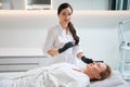 Female esthetician stands with syringe in her hand near patient