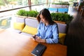 Female european student sitting at cafe with notebook on table and using smartphone.