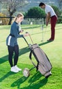 Female examining clubs while male hitting ball Royalty Free Stock Photo