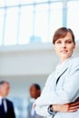 Female executive standing casually with colleagues in background. Business woman smiling while standing with arms folded Royalty Free Stock Photo