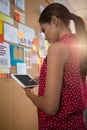 Female executive using digital tablet near bulletin board