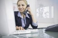 Female executive using phone and computer at office