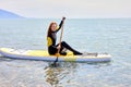 Female experienced surfer on SUP board at sea. Young woman on stand up paddleboard