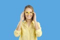 Portrait of happy teen girl wearing fashionable yellow glasses isolated on blue background.