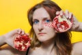 Female face with applied red makeup. Woman and two halves of garnet on a yellow background. Girl and fruit on a yellow background Royalty Free Stock Photo