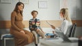 Female Family Doctor Talking with Young Pregnant Woman and Her Teenage Boy with Broken Arm During Royalty Free Stock Photo