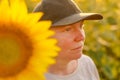 Female farm worker with trucker's hat in blooming sunflower field. Agriculture and farming concept