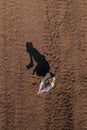 Female farmer examining ploughed field soil, drone photography top view