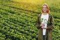 Female farmer holds in hands soybean plant with health leaves and roots, looks at camera at soya field. Agronomist Royalty Free Stock Photo