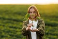 Female farmer holds in hands soybean plant with health leaves and roots, looks at camera at soya field. Agronomist Royalty Free Stock Photo