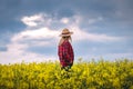 Female farmer is looking at blooming rapeseed field during sunset Royalty Free Stock Photo