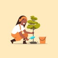 Female farmer planting young tree african american gardener woman digging soil working in garden agricultural gardening