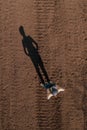 Female farmer standing in ploughed field casting long shadow on the ground Royalty Free Stock Photo