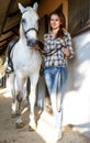 Female farmer standing with white horse at stable outdoor Royalty Free Stock Photo