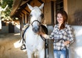 Female farmer standing with white horse at stable outdoor Royalty Free Stock Photo