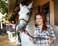 Female farmer standing with white horse at stable outdoor Royalty Free Stock Photo